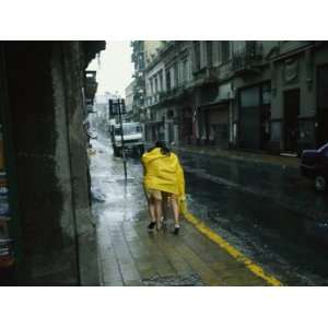 Two People Share a Raincoat as They Hurry Down a Rainy 