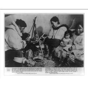   Eskimo domestic scene   woman cooking over seal oil lamp; man carving